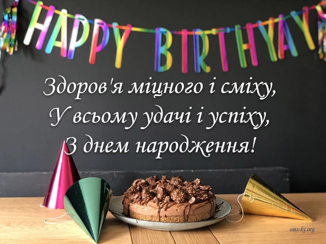 Чорний фон з написом привітання українською та тортам на столі.
