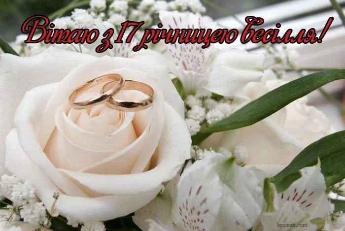 Білі троянди та весільні кільця на фоні букету.