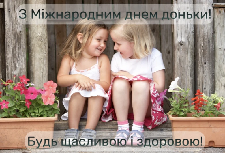 Дві дівчинки сидять між квітками з привітанням на Міжнародний день доньки.